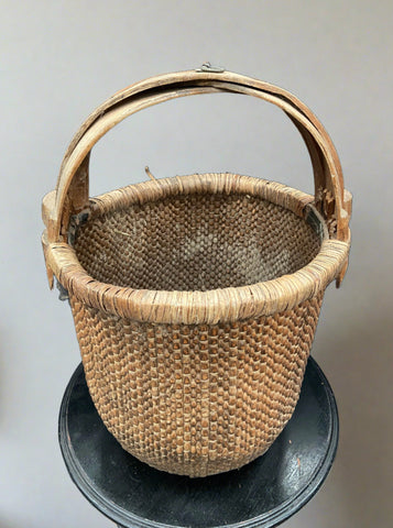 Chinese rice basket crafted from tightly woven willow with a bent bamboo handle. The handle is marked with hand-painted Chinese characters. There is also a metal ring at the top which would have been used to hang the basket. Circa early 20th century.