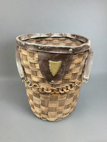 Medieval-style basket woven with thick reeds, with a leather and rusty chain handle.