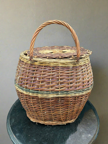 Rustic lidded forager's basket woven with green and pink stained wicker.