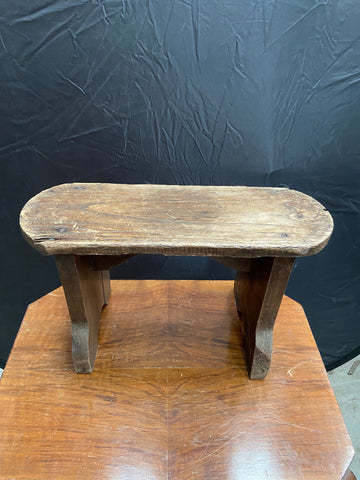 Rustic wooden stool with an oblong seat. 