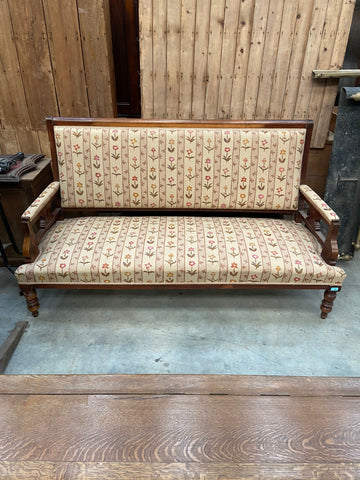 Victorian settee with a dark-turned wooden frame and striped cream floral upholstery. 