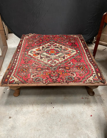 Low floor coffee table with a red woven tapestry/carpet top.&nbsp;
