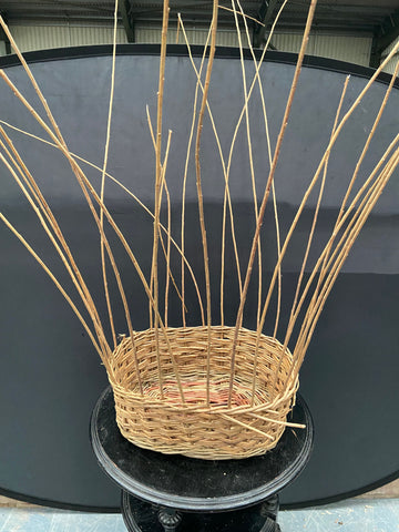 Tall unfinished oval wicker planter.