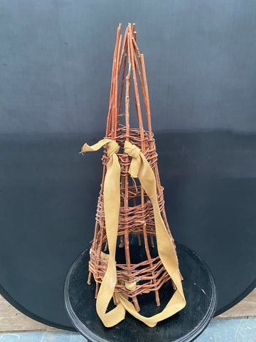 Woven willow plant supports in an obelisk shape with fabric straps.&nbsp;