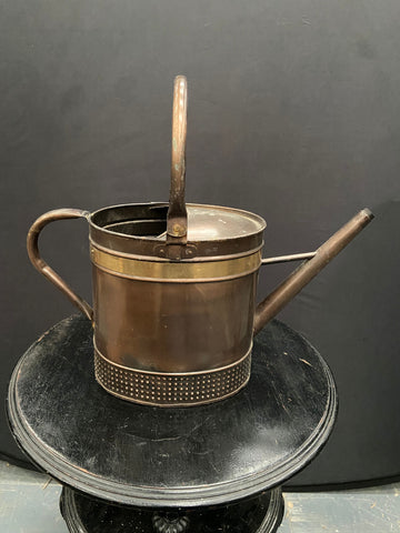 Vintage copper watering can with a decorative brass strip and textured bottom.&nbsp;