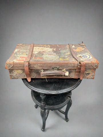 Vintage brown leather suitcase decorated with aged collaged paperwork and stickers.&nbsp;