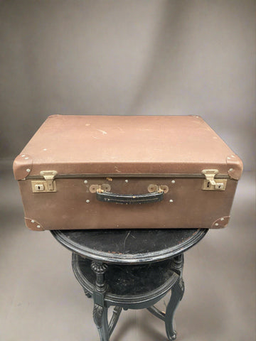 Vintage brown metal suitcase with a black leather handle and aged patina.