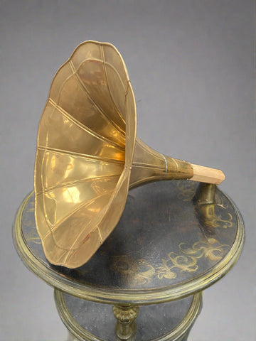 Antique curved brass gramophone horn mounted on a wooden pole.