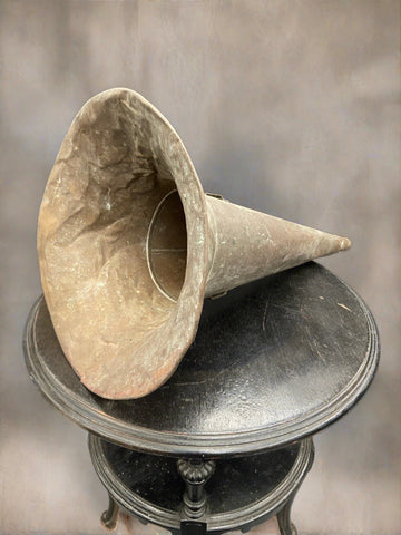 Dented old gramophone horn cast in a cone shape.
