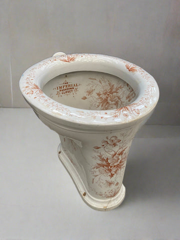 The Imperial washdown closet porcelain toilet, circa the early 20th century. Decorated with burnt orange and white floral patterns.