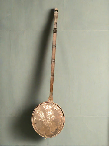 Shiny copper bed warming pan with a turned wooden handle.