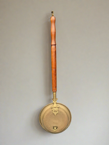 Victorian copper bed warming pan with a shiny wooden handle.