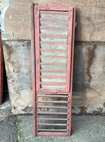Large pink painted window shutters in an aged condition.
