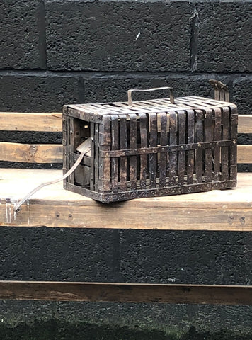 Small metal animal cage with studding detail and aged finish.
