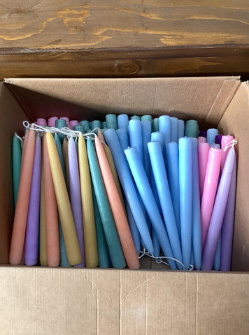 Assorted pastel coloured taper dinner candles.