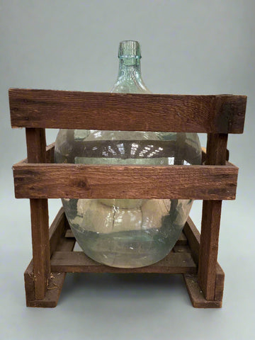 Large demijohn glass bottle encased in a square wooden crate Film TV Props London