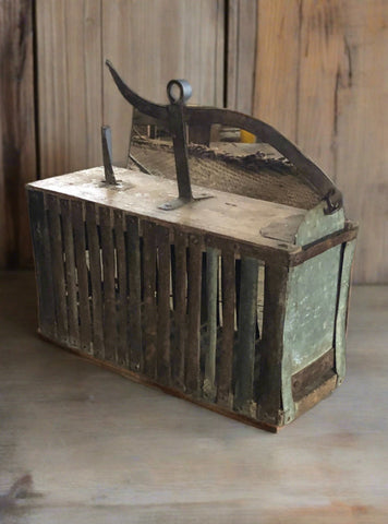 Galvanised metal mechanical animal trap with rusted patina.