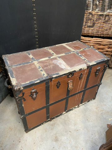 Large brown and black gridded steamer trunk with metal medieval-style hardware.