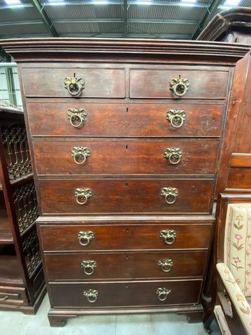 Eight-drawer wooden dresser with ornate brass round ring handles and lockable drawers.