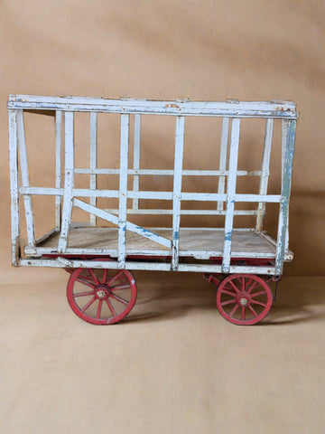 Wooden painted cart for transportation of animals with red wheels.