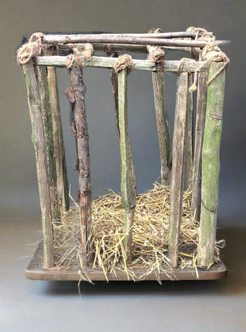 Rustic chicken cage made of branches bound with hemp string and a base layer of straw.