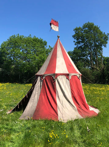 Medieval-style jousting tournament tent in red and white with scalloped trim and pennant flag.