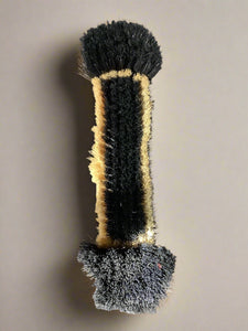 Shoe shining brush with black and white bristles.