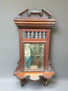 English Edwardian wall-mounted valet mirror with a serpentine shelf and bevel edged mirror, likely carved from walnut. Lots of decorative carved detailing and turned spindle balustrade. Would have been used for shaving.