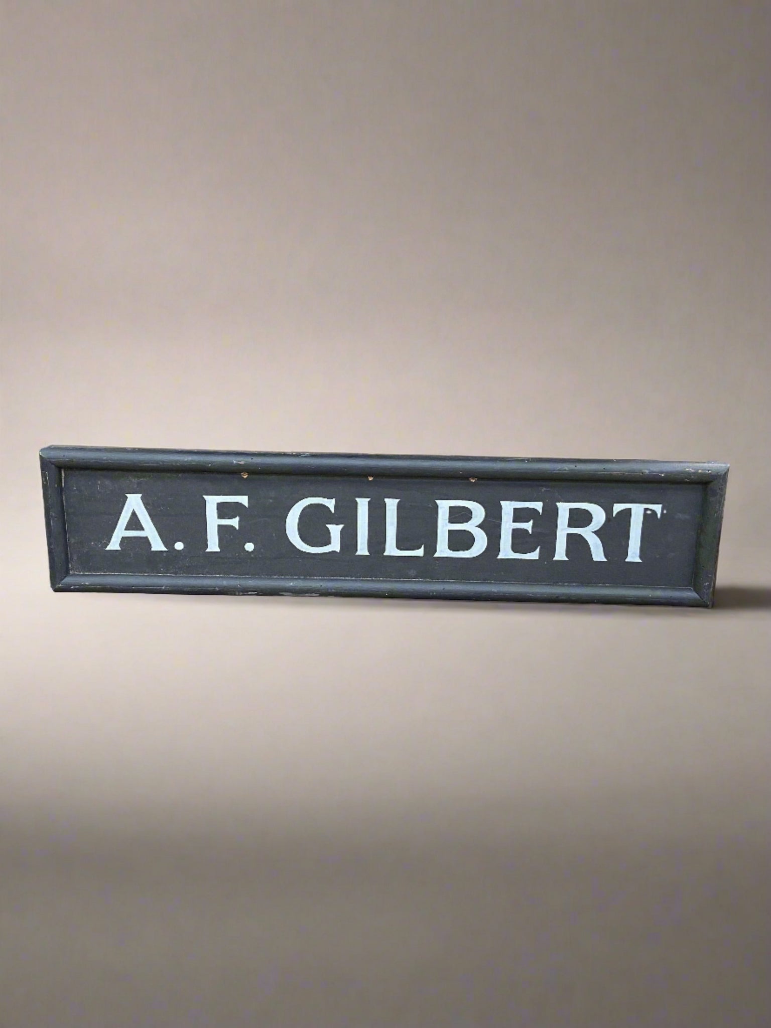 A.F. Gilbert white painted letters on a black wooden board.