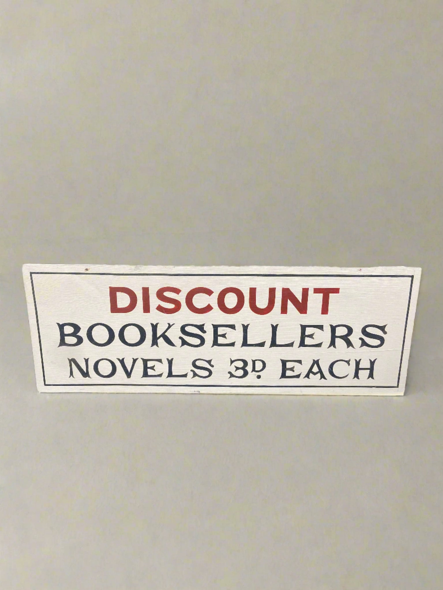 Discount Booksellers sign hand-painted on a wooden backboard.