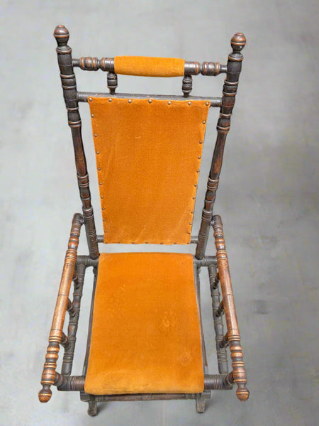 American Child's rocking chair, upholstered in a bright orange fabric with a long lathed frame. An antique piece from the 1800s.