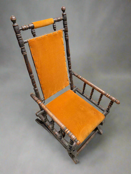 American Child's rocking chair, upholstered in a bright orange fabric with a long lathed frame. An antique piece from the 1800s.