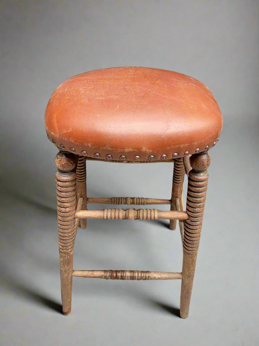 Orange leather studded stool with ornately turned legs.