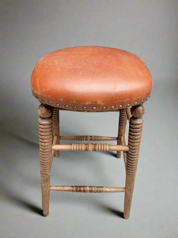 Orange leather studded stool with ornately turned legs.