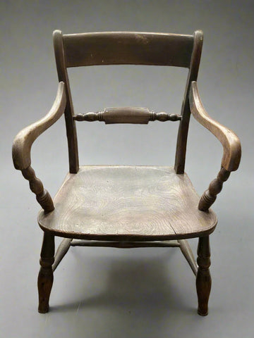 Antique wooden country dining chair with curved arms and an unvarnished finish.