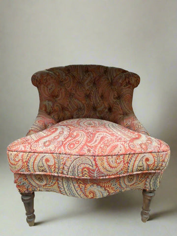 Pink paisley lounge chair with a low buttoned back.