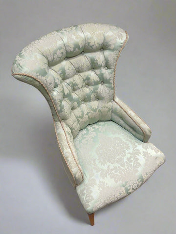 Large buttoned back armchair upholstered in ice blue damask fabric.