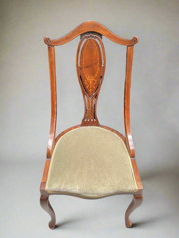 A set of Edwardian dining chairs with a delicate inlaid wood design and sage green seats.