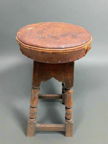 Antique wooden framed stool with a studded leather seat.