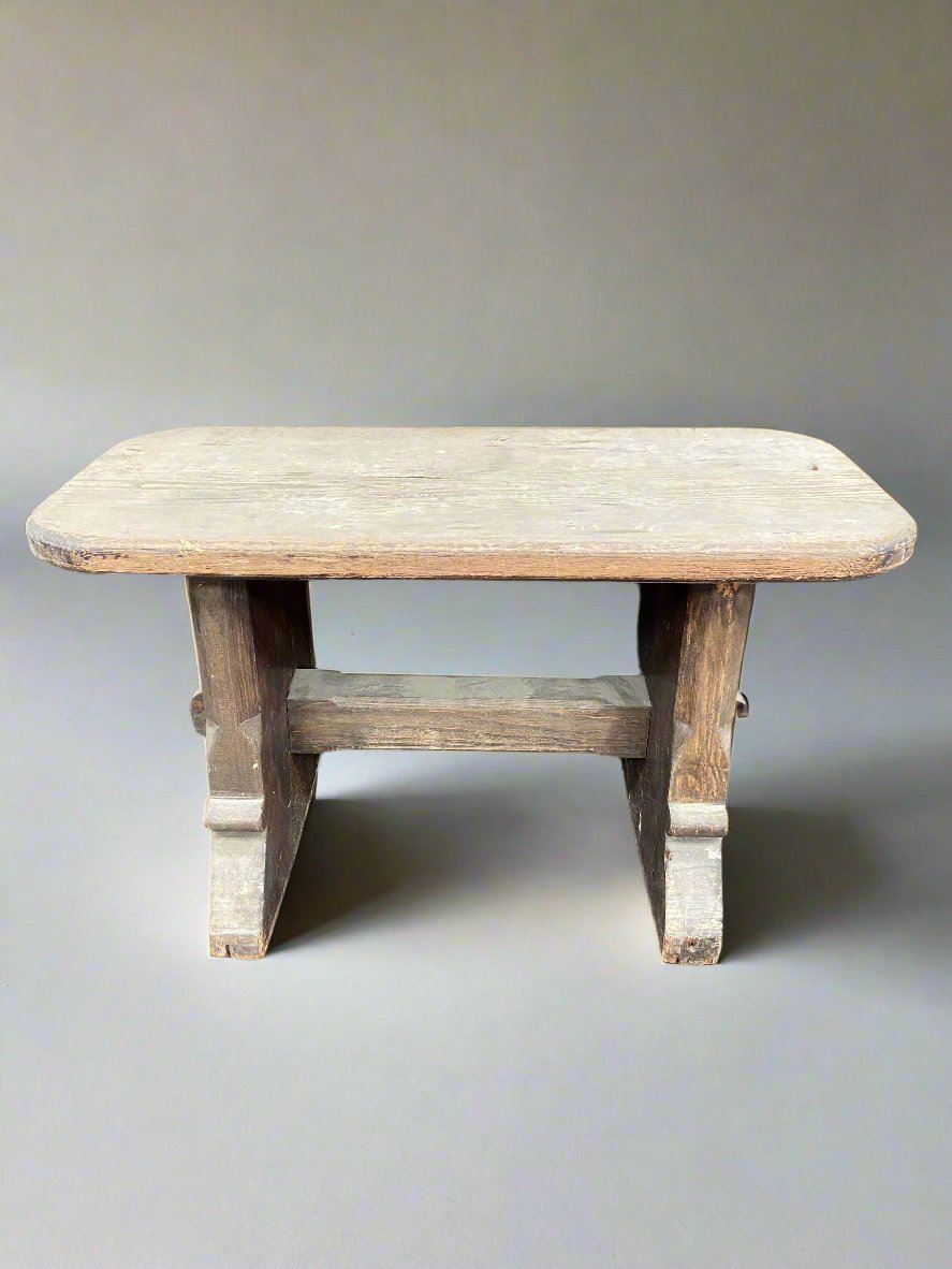 Simple wooden stool with curved corners and an unvarnished rustic finish.