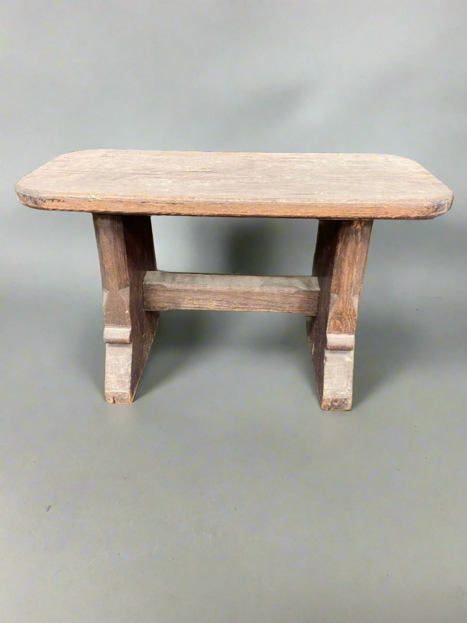 Small rustic wooden bench with a natural unvarnished finish.