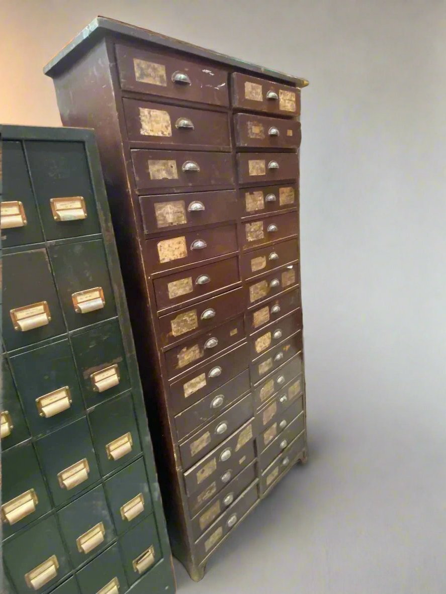 Tall vintage wooden work drawers with faded paper labels and dome handles.