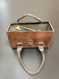 Aged tan leather bag, tied close with a brass buckle. Currently filled with spools of thick thread and wire.