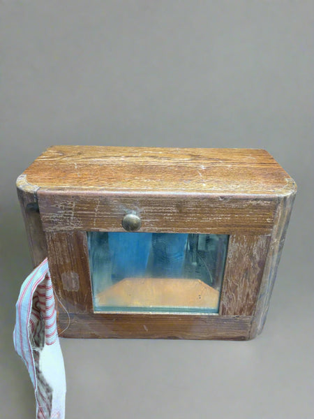 Vintage hand towel dispenser encased in a wooden unit with a mirror.