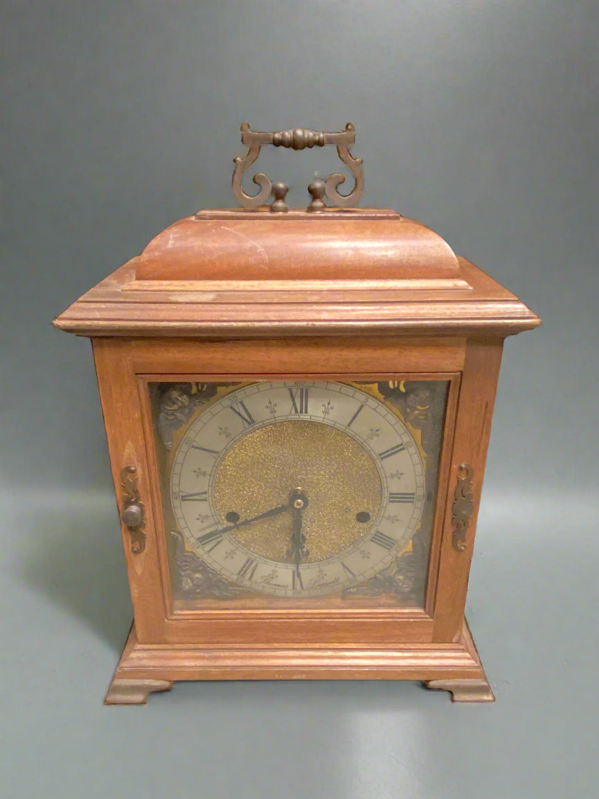 Antique bracket/ mantel clock, decorated with a golden face and cherubs in each corner.