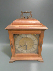 Antique bracket/ mantel clock, decorated with a golden face and cherubs in each corner.