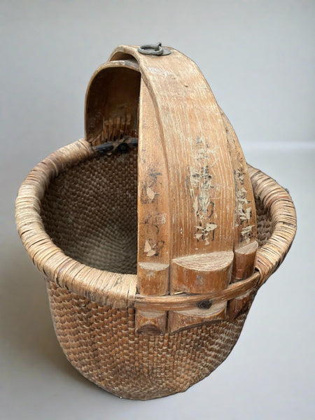 Chinese rice basket crafted from tightly woven willow with a bent bamboo handle. The handle is marked with hand-painted Chinese characters. There is also a metal ring at the top which would have been used to hang the basket. Circa early 20th century.