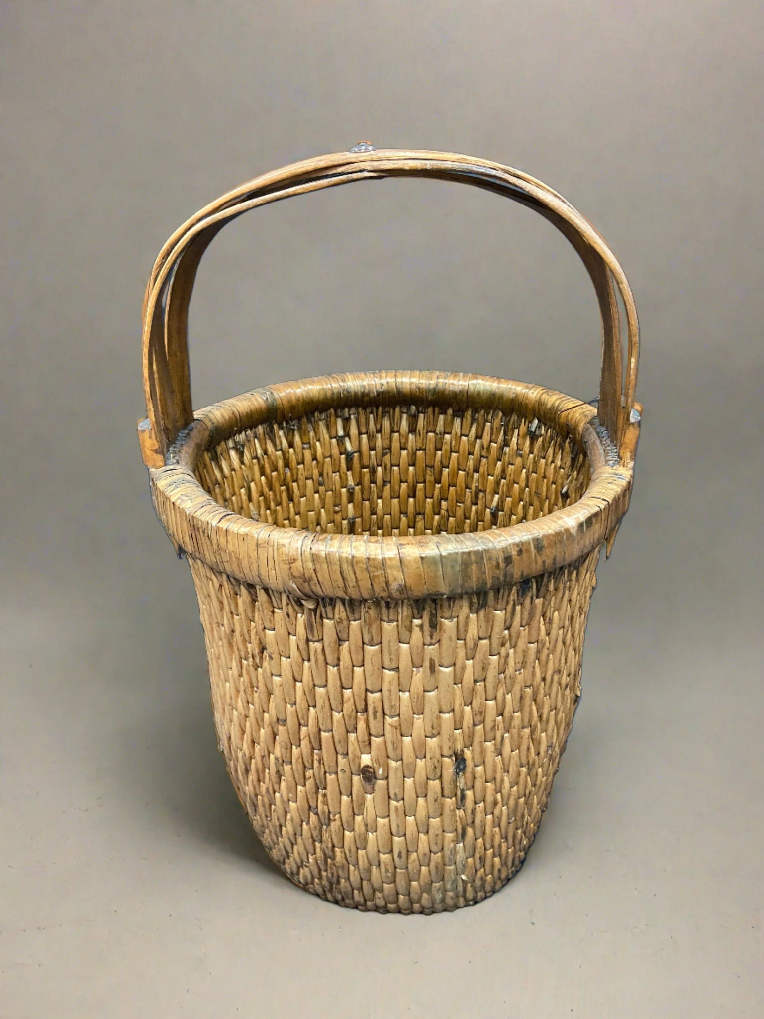 Chinese rice basket crafted from tightly woven willow with a bent bamboo handle. Circa early 20th century. We have a similar larger rice basket that has painted Chinese characters on the handle.