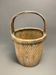 Chinese rice basket crafted from tightly woven willow with a bent bamboo handle. Circa early 20th century. We have a similar larger rice basket that has painted Chinese characters on the handle.