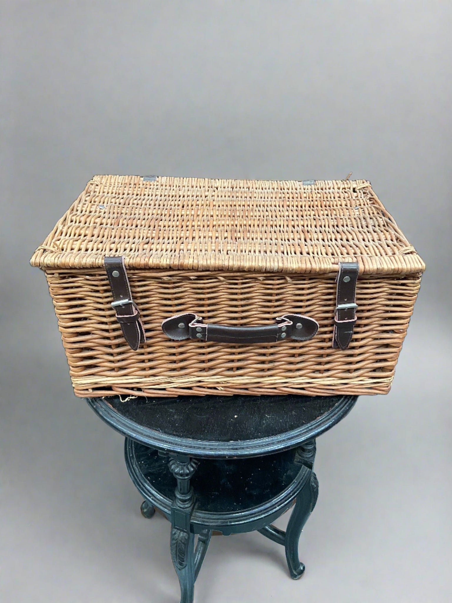 Vintage wicker picnic basket with leather straps and handle.